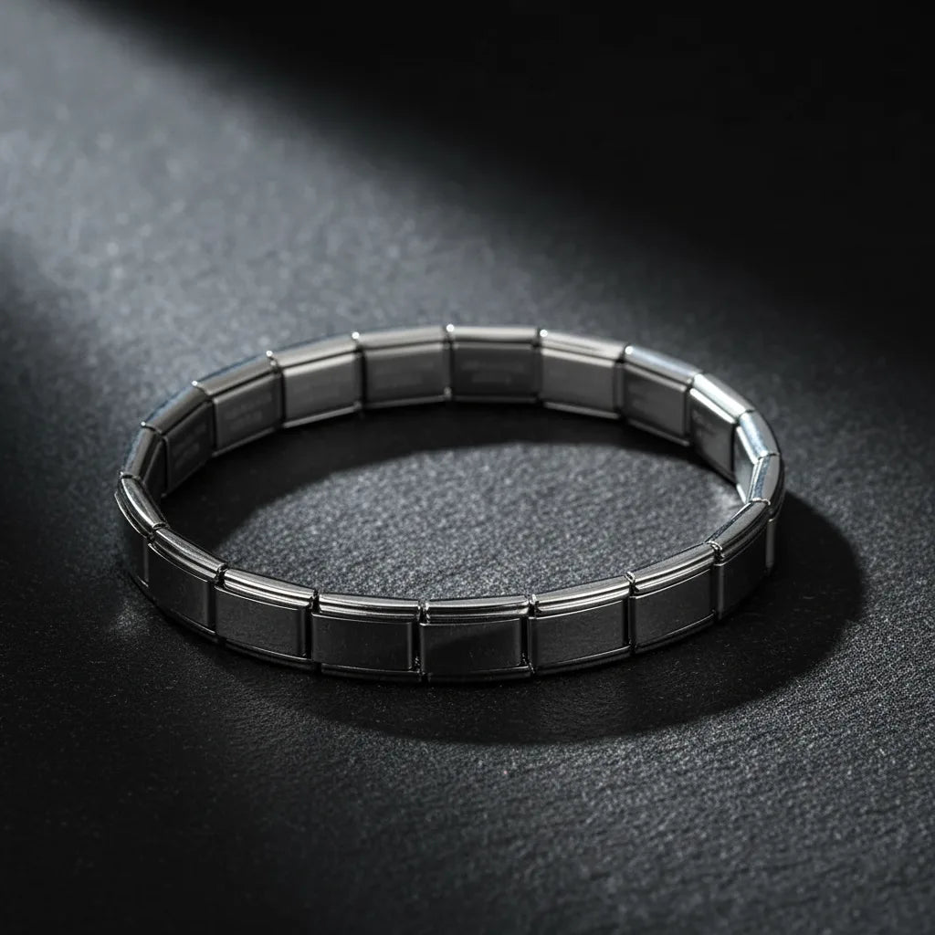 Dramatic studio image of a silver stainless steel stretch bracelets bracelets under a focused beam of light on a dark textured background, emphasizing its glossy metallic shine and flexible stretch construction | Oria Jewel