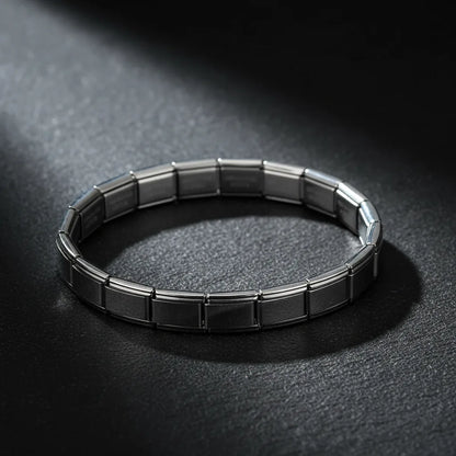 Dramatic studio image of a silver stainless steel stretch bracelets bracelets under a focused beam of light on a dark textured background, emphasizing its glossy metallic shine and flexible stretch construction | Oria Jewel