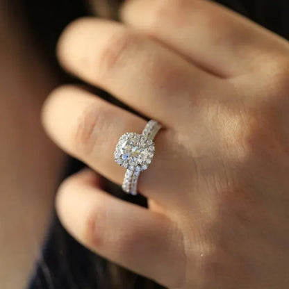 Soft Shine Halo Ring worn on a hand, featuring a round center stone with a sparkling halo frame and a double pavé band, shot in warm natural light with a soft blurred background | OriaJewel