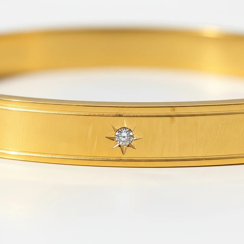 Macro close-up of the gold band of a statement cuff bracelet featuring a tiny starburst setting with a round crystal at the center, showcasing fine detailing and shine | Oria Jewel