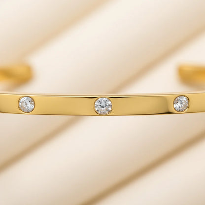 Macro close-up of a thin gold cuff bracelet focusing on the round bezel-set crystals along the smooth polished band, emphasizing its refined shine and delicate detailing | Oria Jewel